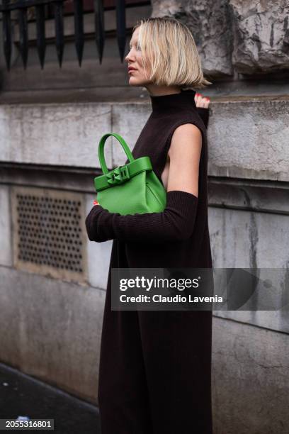 Violet Grace Atkinson, wears brown turtleneck long sweater dress, matching arm warmers, green Hermes bag, outside Hermes, during the Womenswear...