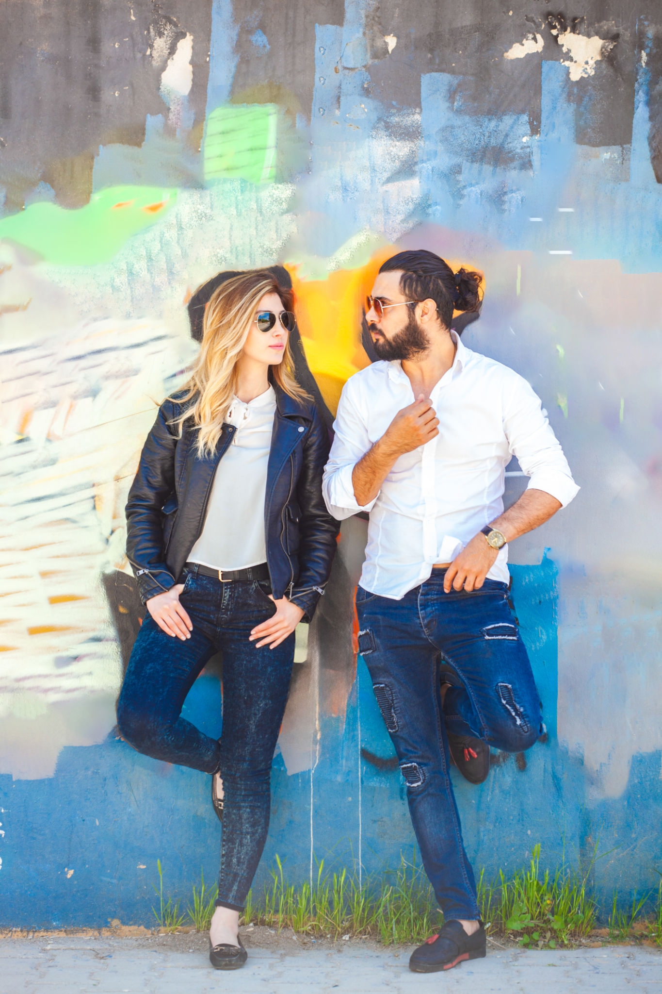 Young and free. Young stylish couple leaning on the wall behind them. Young and free. Young stylish couple leaning on the wall behind them.