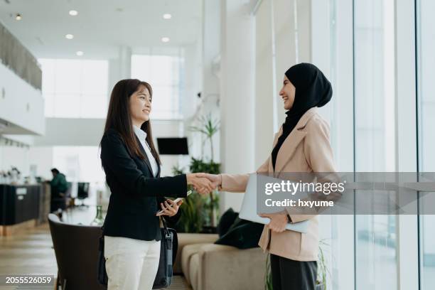 businesswomen shake hands in office - malay people stock pictures, royalty-free photos & images
