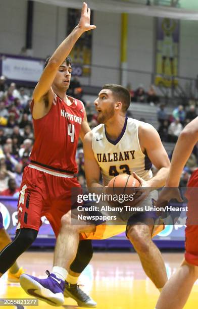 University at Albany's Greig Stire is guarded by Hartford's George Blagojevic as he drives to the basket during a basketball game at SEFCU Arena on...