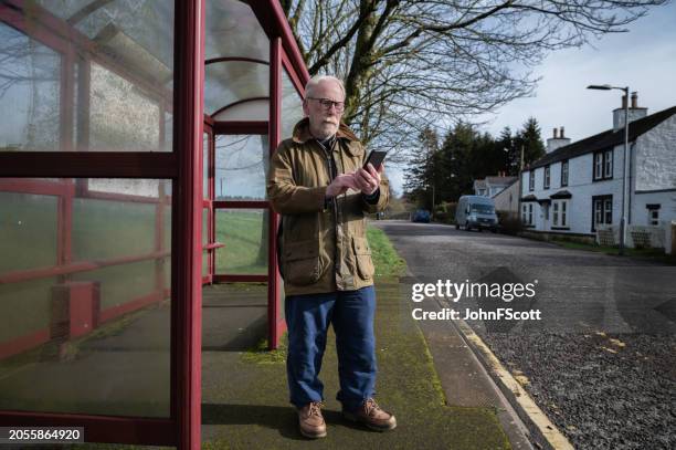 senior man standing at a bus stop - waxed jacket stock pictures, royalty-free photos & images