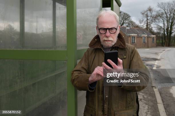 senior man checking his mobile phone - waxed jacket stock pictures, royalty-free photos & images