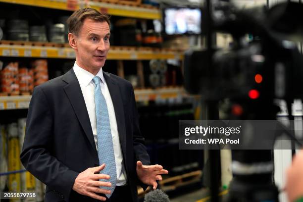 Chancellor Jeremy Hunt gestures as he speak to a Tv reporter during a visit to a builders warehouse on March 6, 2024 in London, England.