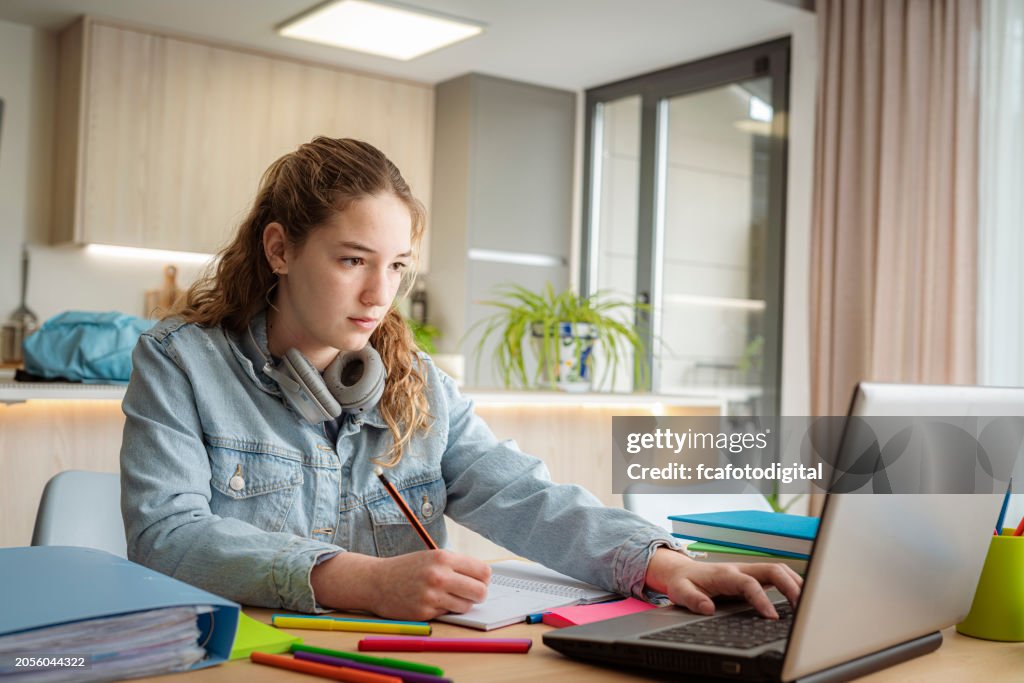 Adolescente haciendo tareas escolares usando una computadora portátil en casa
