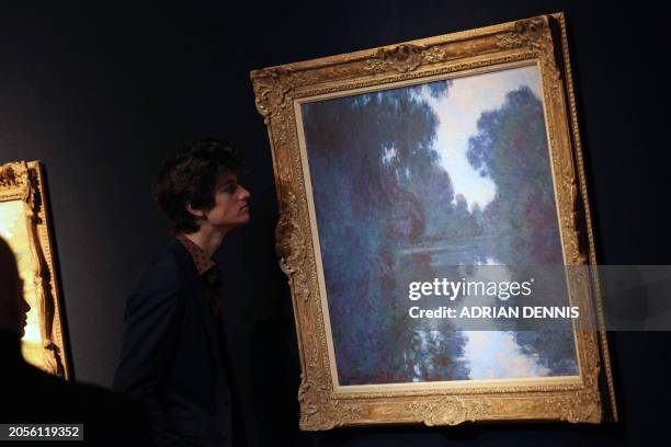 Gallery staff member examines an artwork entitled "Matinée sur la Seine, temps net" by French artist Claude Monet at Christie's auctioneers in...