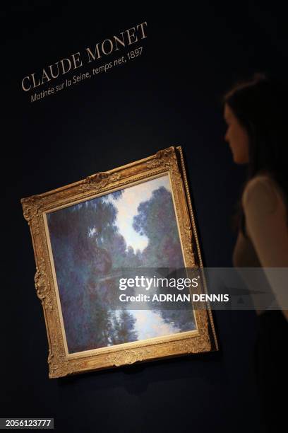 Gallery staff member examines an artwork entitled "Matinée sur la Seine, temps net" by French artist Claude Monet at Christie's auctioneers in...