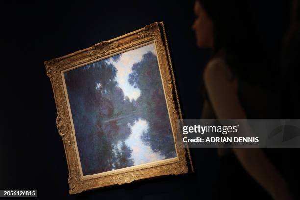 Gallery staff member examines an artwork entitled "Matinée sur la Seine, temps net" by French artist Claude Monet at Christie's auctioneers in...