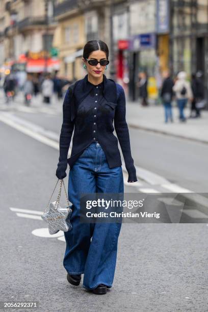 Guest wears star shaped Chanel bag, wide leg dark blue denim jeans, button up knit outside Akris during the Womenswear Fall/Winter 2024/2025 as part...