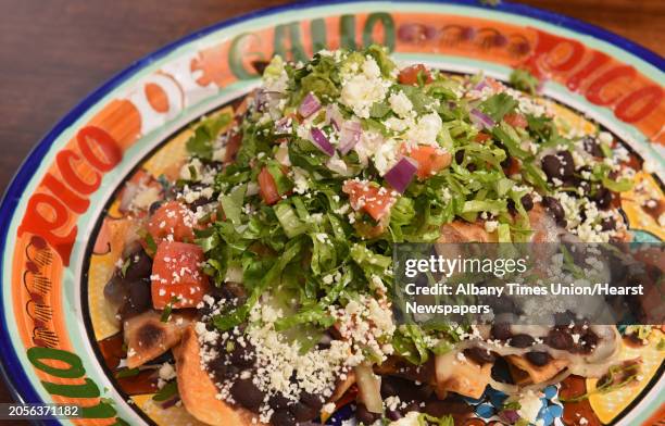 Nachos - fresh mountain of homemade corn tortilla chips topped with cheese, beans, sour cream, lettuce, pico de gallo and guacamole at Pico de Gallo...