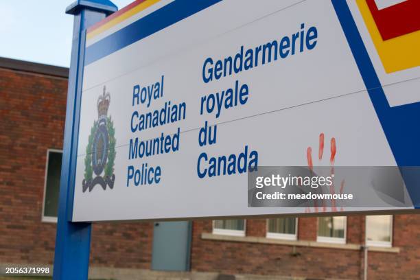 photo of a royal canadian mounted police sign in english and french with a red colored handprint on it - hate engels woord stockfoto's en -beelden