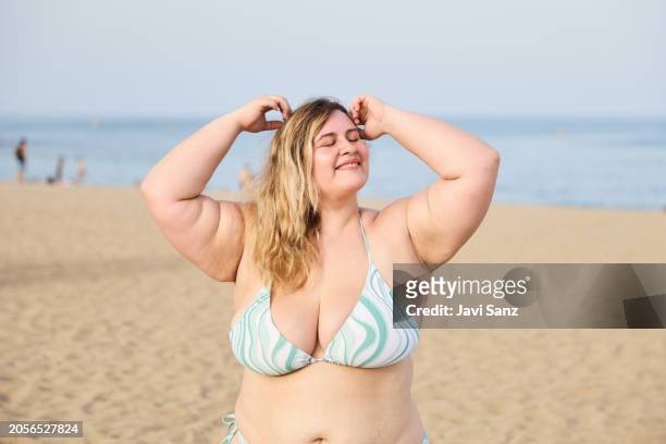 fröhliche fettleibige frau, die an einem sonnigen sommertag ihren kopf am strand berührt - big fat white women stock-fotos und bilder