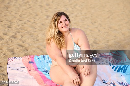 Cheerful young overweight woman on the beach smiling at the camera sitting on the towel on the sand. Cheerful young overweight woman on the beach smiling at the camera sitting on the towel on the sand.