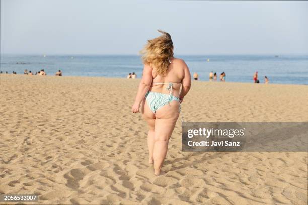 cheerful overweight woman running on the sandy beach with the sea in the background - voluptuoso imagens e fotografias de stock