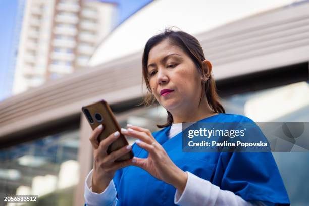 nurse checking something on the phone - filipino people stock pictures, royalty-free photos & images