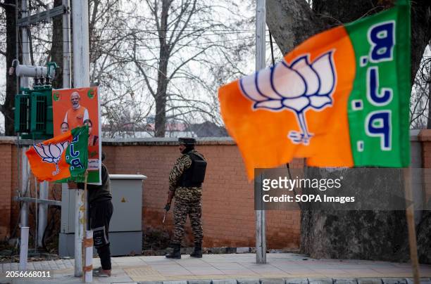 Flags of the Bharatiya Janata Party are seen waving on the street as Indian paramilitary troopers stand alert ahead of Prime Minister Narendra Modi's...