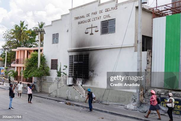 Civilians and press members look at the Delmas Tribunal de Paix, torched by gangs moments after armed gang members exchanged gunfire with police and...