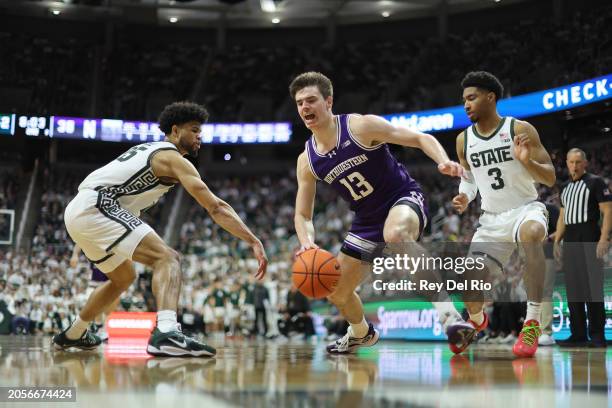 Brooks Barnhizer of the Northwestern Wildcats drives to the basket while defended by Malik Hall and Jaden Akins of the Michigan State Spartans during...