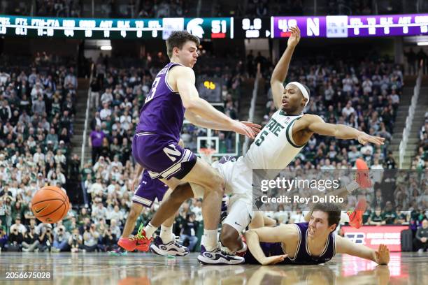 Ryan Langborg and Brooks Barnhizer of the Northwestern Wildcats dives for a loose ball against Tre Holloman of the Michigan State Spartans during the...