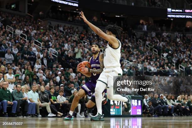 Boo Buie of the Northwestern Wildcats drives past A.J. Hoggard of the Michigan State Spartans during the second half at Breslin Center on March 6,...