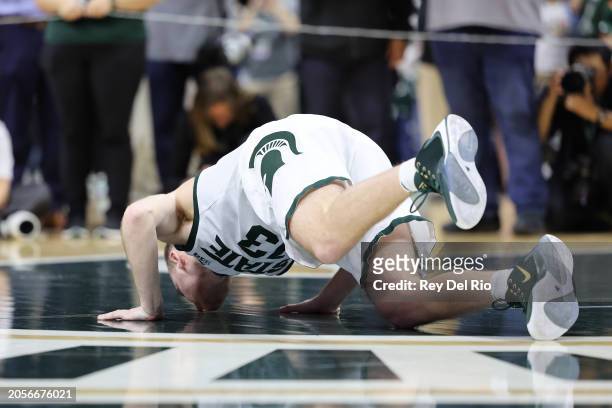 Steven Izzo of the Michigan State Spartans kisses the center court logo on senior day after the game against the Northwestern Wildcats between the...
