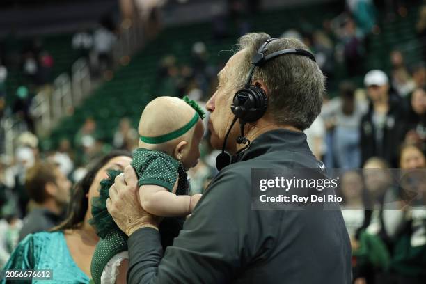 Head coach Tom Izzo of the Michigan State Spartans celebrates his win against the Northwestern Wildcats with his granddaughter on senior day after...