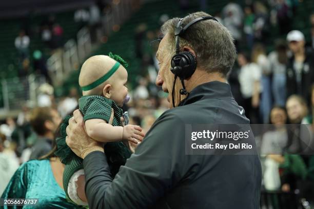 Head coach Tom Izzo of the Michigan State Spartans celebrates his win against the Northwestern Wildcats with his granddaughter on senior day after...