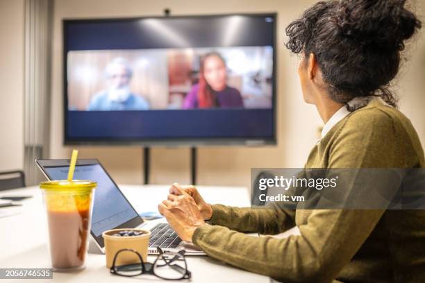 businesswoman attending a virtual meeting in a conference room - conference call stock pictures, royalty-free photos & images