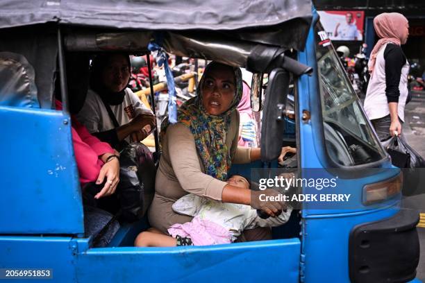 This picture taken on February 25, 2024 shows Bajaj driver and single mother Ekawati, who plies her three-wheeled taxi in a profession overwhelmingly...
