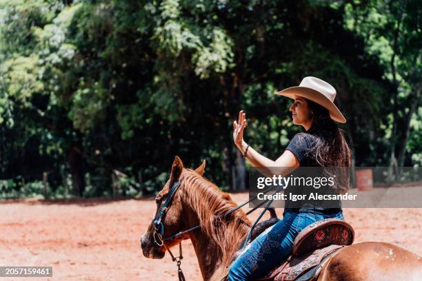 cowgirl waving in the enclosure - animal waving stock pictures, royalty-free photos & images