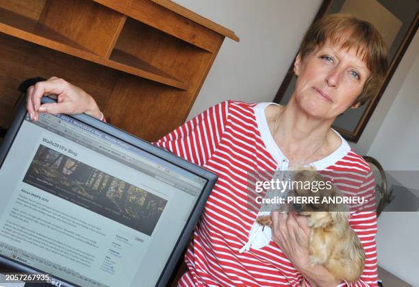 British Maria-Louise Sawyer poses with her dog, next to her computer on March 16, 2011 at her home in the French western village of Chazelles. Left...