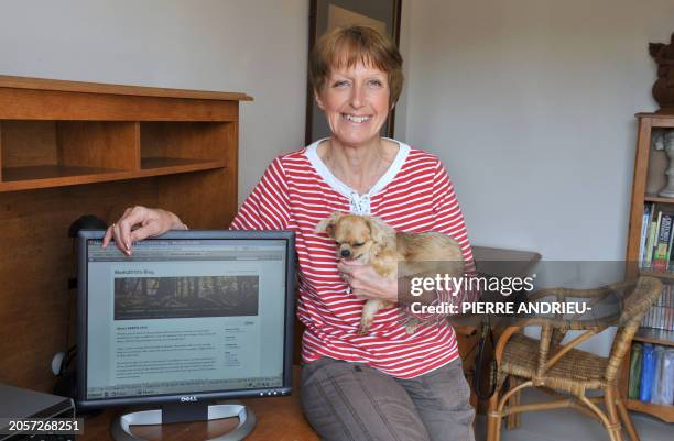 British Maria-Louise Sawyer poses with her dog, next to her computer on March 16, 2011 at her home in the French western village of Chazelles. Left...