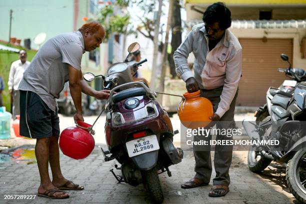 Men load cans of water filled from a municipal tap onto a scooter, amid an ongoing water crisis in Bengaluru on March 7, 2024.