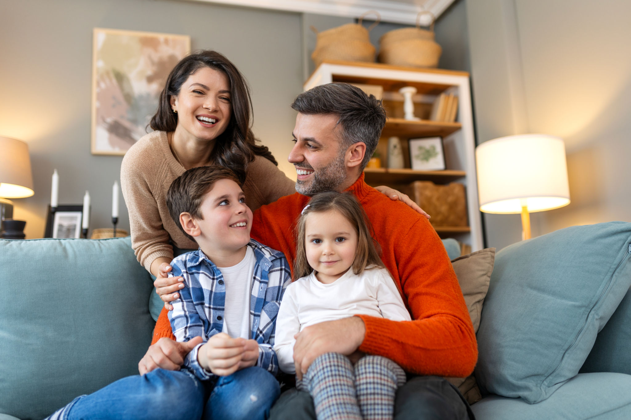 Happy family having fun at home, parents and little children sit on sofa together, Happy family sitting on sofa laughing together. Cheerful parents playing with their kids at home. Happy family having fun at home, parents and little children sit on sofa together, Happy family sitting on sofa laughing together. Cheerful parents playing with their kids at home.