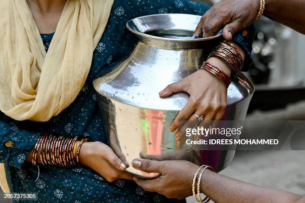 Woman carries a can of water filled from a municipal tap, amid an ongoing water crisis in Bengaluru on March 7, 2024.