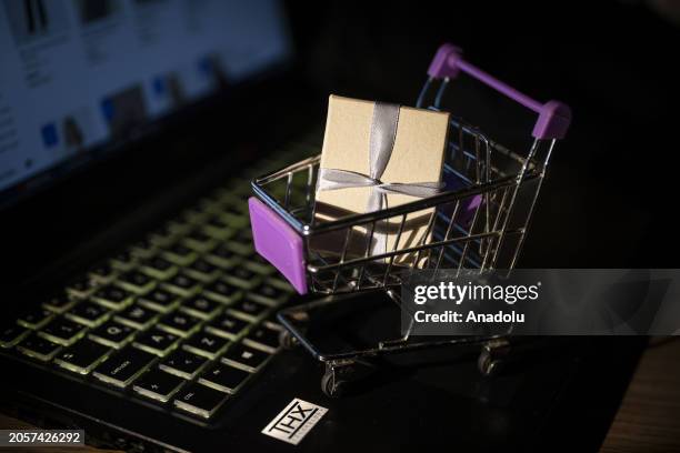 Miniature shopping cart with a gift box is seen on a laptop with its screen displaying an online shopping website in Ankara, Turkiye on March 06,...