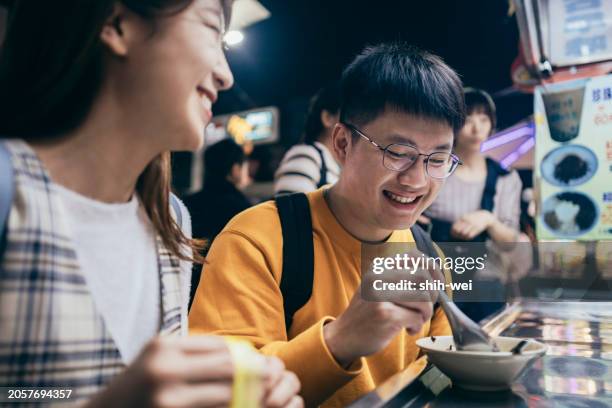 a young asian couple visited a famous local night market and tasted street food in taiwan - street light banner stock pictures, royalty-free photos & images