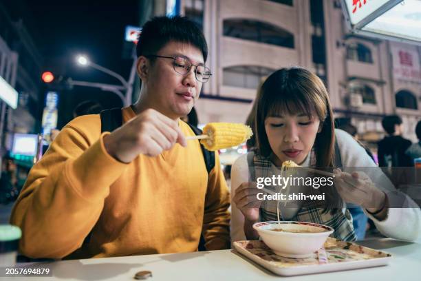 a young asian couple visited a famous local night market and tasted street food in taiwan - street light banner stock pictures, royalty-free photos & images