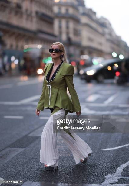 Palina Kozyrava seen wearing Loewe black sunglasses, black large flower earrings, Femif green / black elegant pleated blazer jacket, matching Femif...