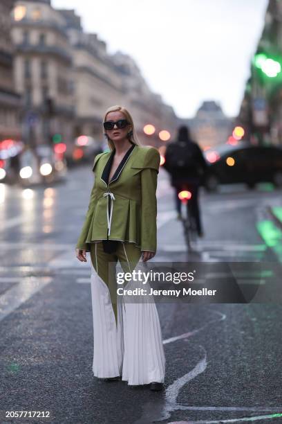 Palina Kozyrava seen wearing Loewe black sunglasses, black large flower earrings, Femif green / black elegant pleated blazer jacket, matching Femif...