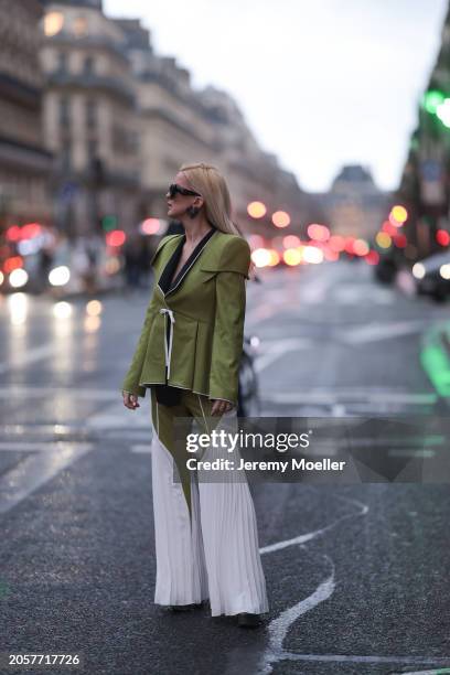 Palina Kozyrava seen wearing Loewe black sunglasses, black large flower earrings, Femif green / black elegant pleated blazer jacket, matching Femif...