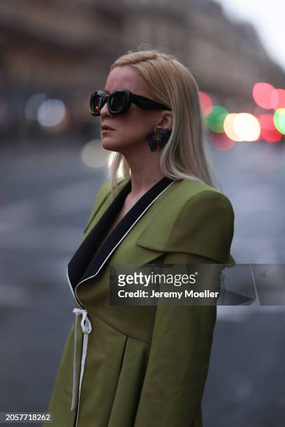 Palina Kozyrava seen wearing Loewe black sunglasses, black large flower earrings, Femif green / black elegant pleated blazer jacket, during the...