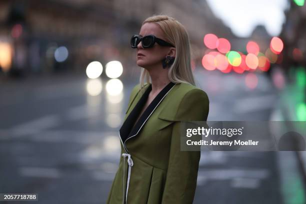 Palina Kozyrava seen wearing Loewe black sunglasses, black large flower earrings, Femif green / black elegant pleated blazer jacket, during the...