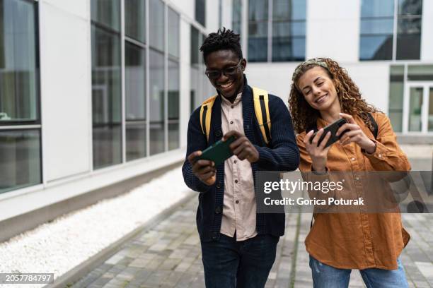 amis souriants jouant à un jeu en ligne sur smartphone - jeu mobile photos et images de collection