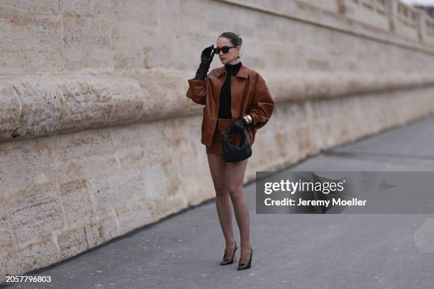 Berna Bilbey seen wearing YSL black sunglasses, gold earrings, COS black turtleneck top, Lioness brown oversized leather jacket, matching Lioness...