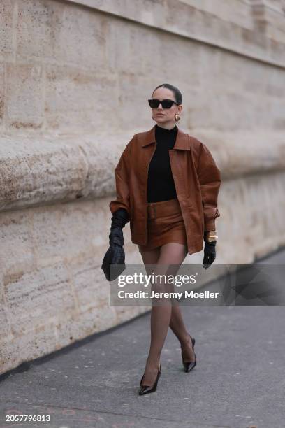 Berna Bilbey seen wearing YSL black sunglasses, gold earrings, COS black turtleneck top, Lioness brown oversized leather jacket, matching Lioness...