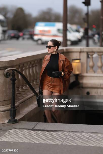 Berna Bilbey seen wearing YSL black sunglasses, gold earrings, COS black turtleneck top, Lioness brown oversized leather jacket, matching Lioness...