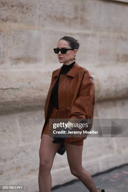 Berna Bilbey seen wearing YSL black sunglasses, gold earrings, COS black turtleneck top, Lioness brown oversized leather jacket, matching Lioness...