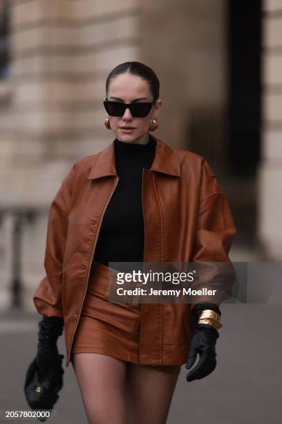 Berna Bilbey seen wearing YSL black sunglasses, gold earrings, COS black turtleneck top, Lioness brown oversized leather jacket, matching Lioness...