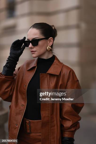 Berna Bilbey seen wearing YSL black sunglasses, gold earrings, COS black turtleneck top, Lioness brown oversized leather jacket, matching Lioness...