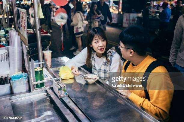 a young asian couple visited a famous local night market and tasted street food in taiwan - street light banner stock pictures, royalty-free photos & images